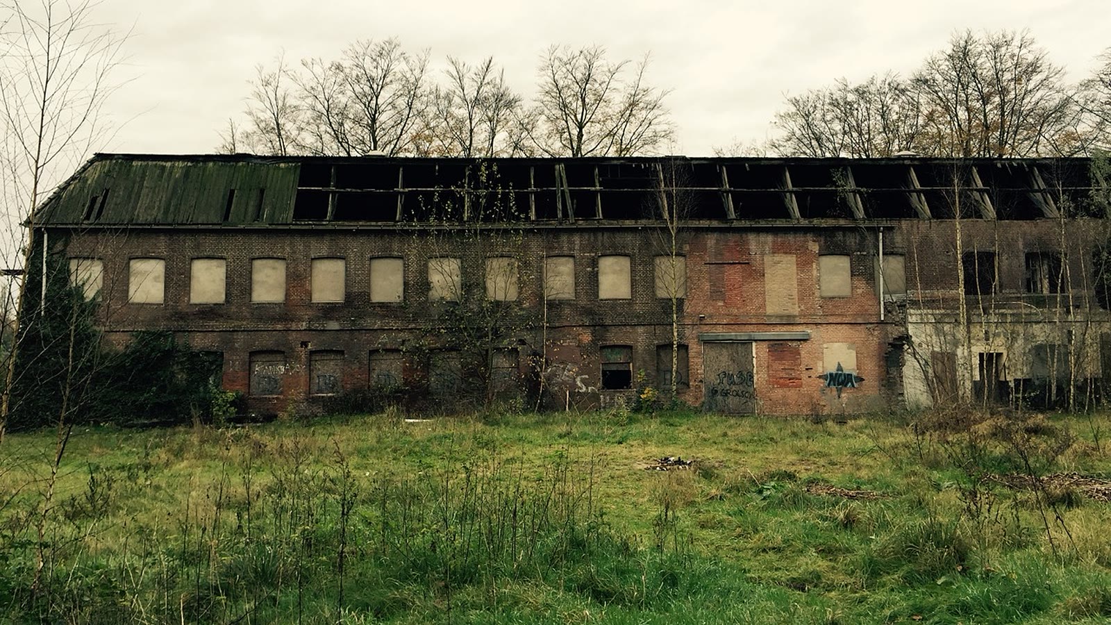 Die Fabrik während des Leerstands, mit kaputtem Dach und vernagelten Fenstern